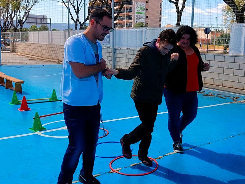 Chico_del_centro_de_dia_de_Astrapace_trabajando_con_el_enfermero_y_su_tutora_en_el_patio