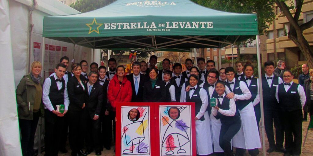 Voluntarios_y_profesionales_en_las_jornadas_gastronomicas_de_astrapace_posando_junto_al_toldo_de_estrella_de_levante